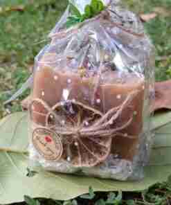 Vela aromática empaquetada sobre hojas verdes.