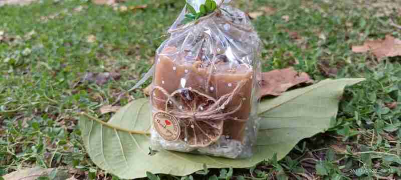Vela aromática empaquetada sobre hojas verdes.