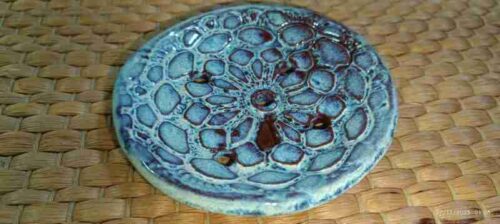 Posavasos cerámico azul sobre fondo mimbre.